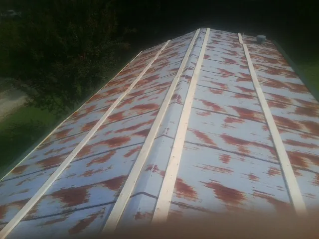Rusted metal roof panels with new wood purlins before replacement — Storm Damage Roof Repair in Holdingford by Roofing Brothers
