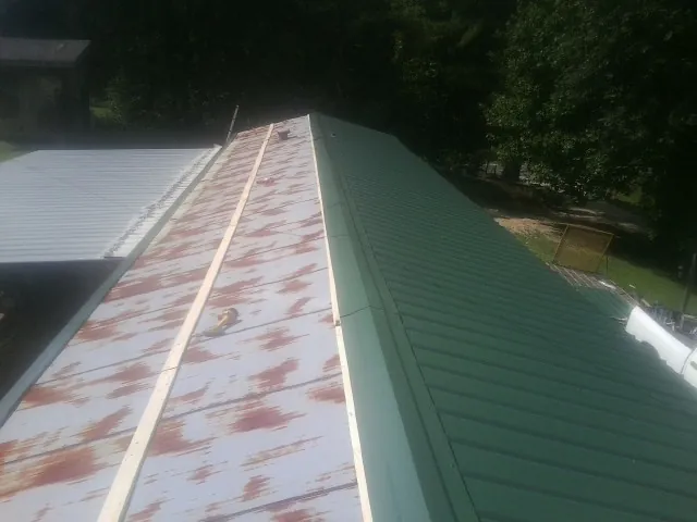 Old rusted panels beside newly installed green metal roofing — Wind Damage Roof Repair by Roofing Brothers in Holdingford