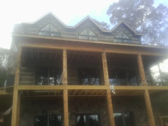 Dormers and porch framing on a large log home under construction — Roof Coating work by our crew in Holdingford