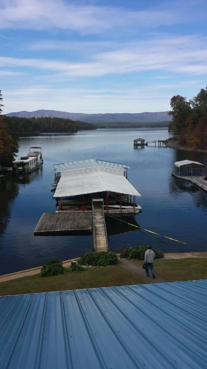 View across a lake from a newly installed blue metal roof in Holdingford