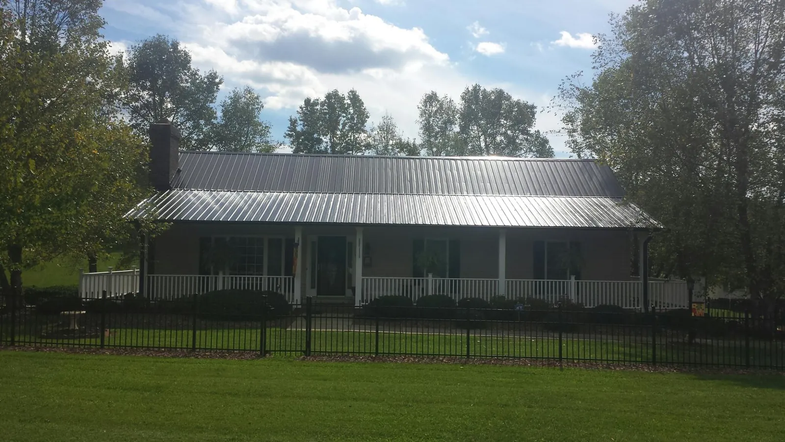 Gray metal roof on a brick ranch with a full width front porch — Gutter Guard Installation work by our crew in Holdingford