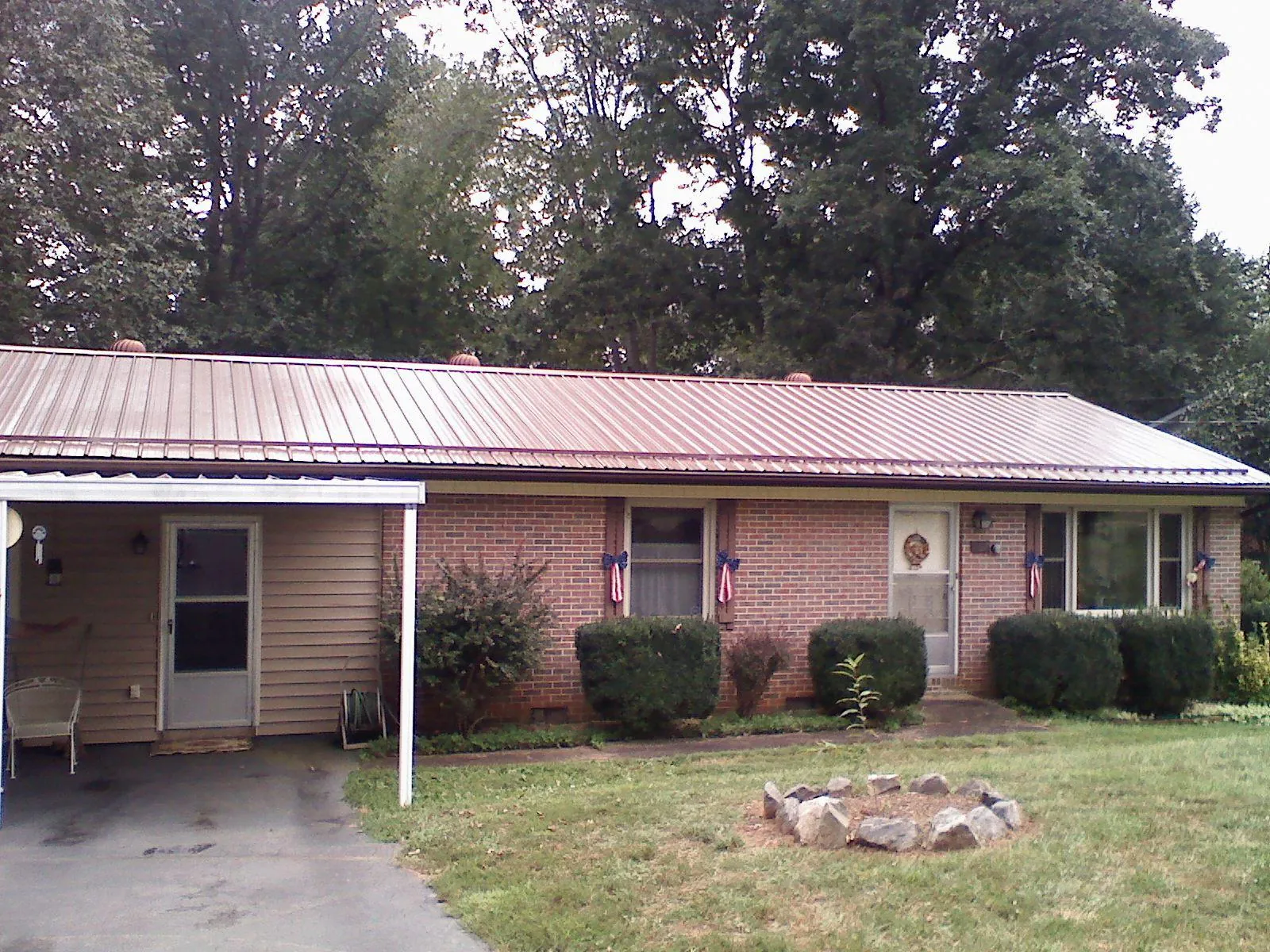 Bronze metal roof and carport on a brick ranch home — Roof Repair work by our crew in Holdingford