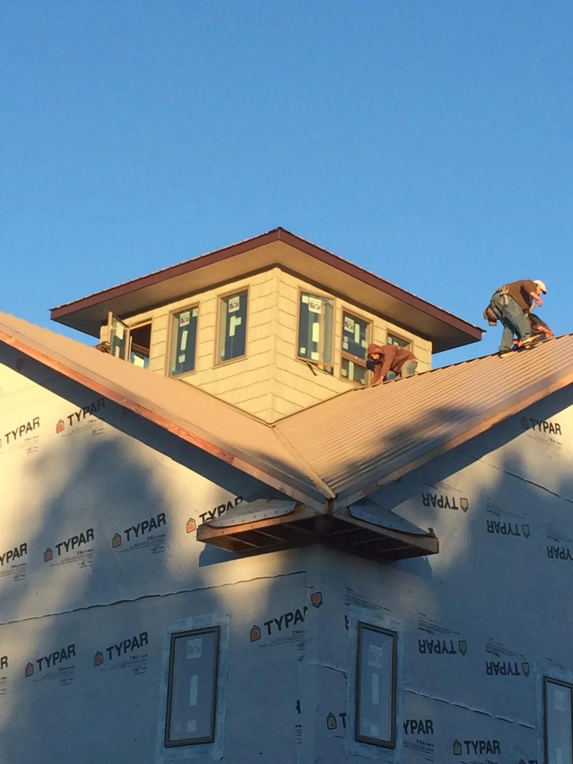 Roofers working around a rooftop cupola on a new metal roof at sunset — Roof Waterproofing in Holdingford by Roofing Brothers
